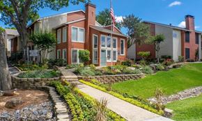 Dallas apartment for rent - A house with a flag on the front porch is surrounded by a garden at Infinity on the Oaks Apartments, Dallas, TX