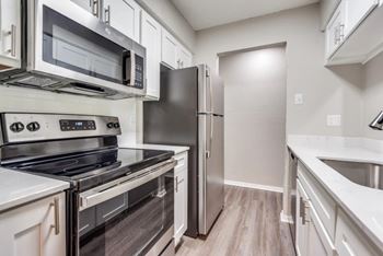A kitchen with a stove, oven, microwave, refrigerator, and sink.