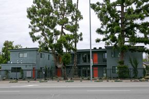 Los Angeles apartment for rent - A grey building with red doors and a black fence.