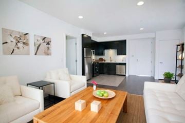 Los Angeles apartment for rent - A modern living room with a wooden coffee table and two white couches.