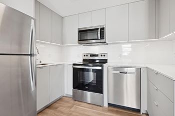 A modern kitchen with stainless steel appliances and white cabinetry.