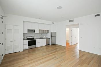 A kitchen with white cabinets and a wooden floor.