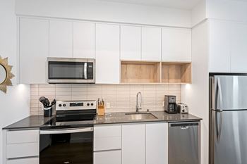 A modern kitchen with white cabinets and stainless steel appliances.