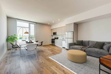 Los Angeles apartment for rent - A modern kitchen with a dining table and chairs is adjacent to a living room with a grey couch and a bean bag.