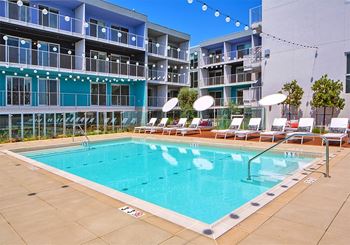 A large swimming pool in front of a multi-story apartment building.