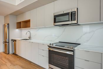 A kitchen with a stainless steel refrigerator, microwave, oven, and sink.