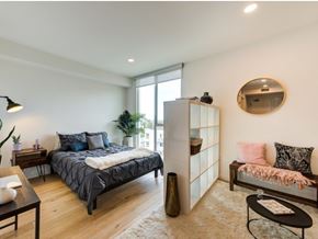 Los Angeles apartment for rent - A bedroom with a bed, a bench, and a mirror on the wall at Prizma in Los Angeles, CA, 90038