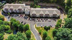 Triangle apartment for rent - An aerial view of a parking lot with cars and a building with a grey roof.