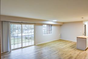 Manassas apartment for rent - A room with wooden floors and a large window with a view of a fence and trees.
