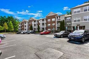 Triangle apartment for rent - A parking lot with cars and apartment buildings in the background.