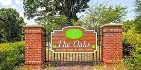 Triangle apartment for rent - A sign for "The Oaks Apartment Homes for Active Seniors" is displayed in front of a brick wall.