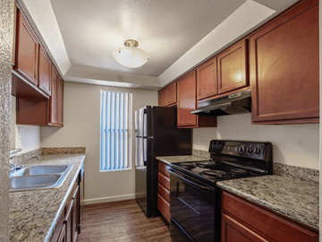 Tempe apartment for rent - A kitchen with brown cabinets and a black stove top oven.