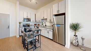 Brentwood apartment for rent - A kitchen with a stainless steel refrigerator, a microwave, and a dining table with chairs.