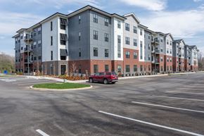 Hermitage apartment for rent - A red car is parked in a parking lot in front of apartment buildings.