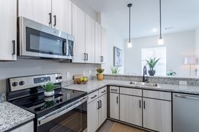 Hermitage apartment for rent - A modern kitchen with a black stove and white cabinets.