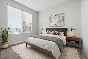 Nashville apartment for rent - A bedroom with a large bed, a potted plant, and a painting on the wall.