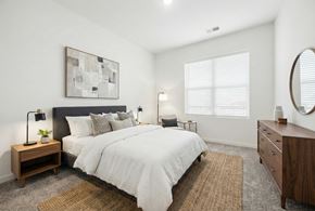 Brentwood apartment for rent - A bedroom with a large bed, a nightstand with a lamp, and a painting on the wall.