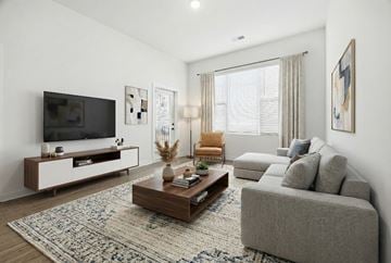 Nashville apartment for rent - A modern living room with a grey sofa, a wooden coffee table, and a television on a white cabinet.