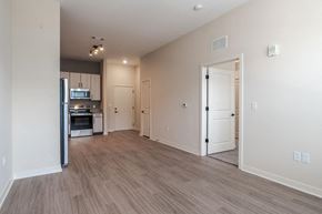 Huntsville apartment for rent - A spacious room with a kitchen area and a door leading to another room.