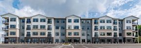 Huntsville apartment for rent - A large, modern apartment building with multiple balconies and a parking lot in front.