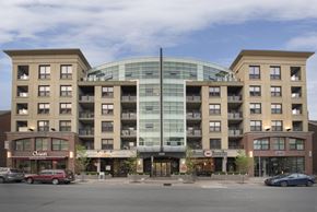 Halifax apartment for rent - A large building with a glass center and a red car in front of it.