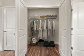 Dover apartment for rent - A white closet with clothes hanging and baskets on the floor.
