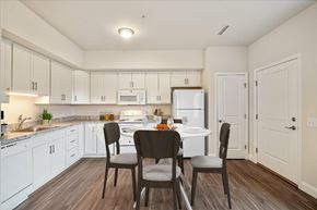 Dover apartment for rent - A kitchen with white cabinets and a table with chairs.