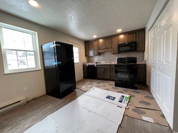 Red Lion apartment for rent - A kitchen with a black fridge, microwave, and oven with cabinets and a window.