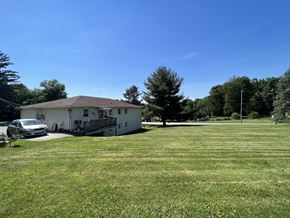 Windsor apartment for rent - A white house with a brown roof is surrounded by a grassy field.