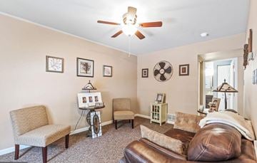 York apartment for rent - A living room with a brown leather couch, a fan, and a table with a picture frame on it.