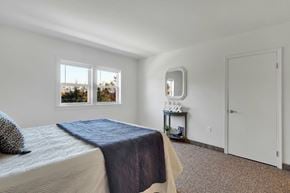 York apartment for rent - A bedroom with a bed, a nightstand with a mirror, and a window.