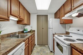 Indiana apartment for rent - A kitchen with brown cabinets and a white stove top oven.