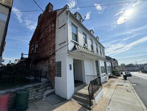 Wrightsville apartment for rent - A white house with a black iron fence is in front of a brick building.
