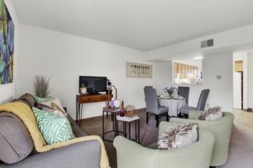 Indiana apartment for rent - A living room with a grey couch, a white dining table and chairs, and a television.