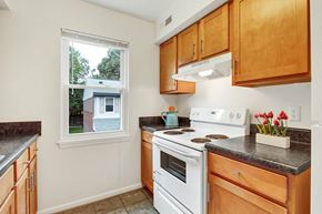 Virginia Beach apartment for rent - A kitchen with wooden cabinets and a white stove top oven.