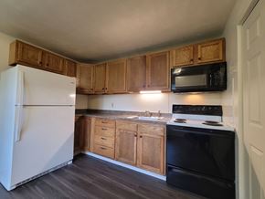 Mount Wolf apartment for rent - A kitchen with a white refrigerator, black oven, and wooden cabinets.