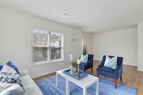 York apartment for rent - A living room with a white couch, blue chairs, and a white coffee table.