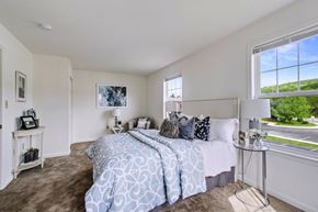 York apartment for rent - A bedroom with a large bed and a window overlooking a green landscape.