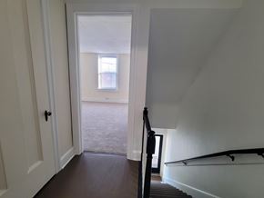 Wrightsville apartment for rent - A hallway with a black railing and a white door.