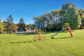 Indiana apartment for rent - A playground with a blue slide, a red slide, and a yellow and red climbing frame.