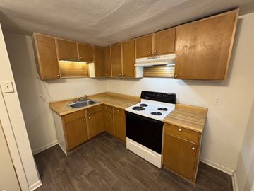 Windsor apartment for rent - A small kitchen with wooden cabinets and a black stove top.