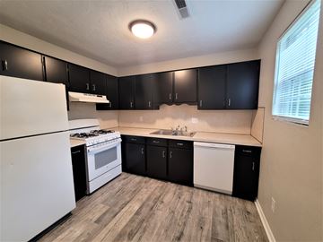York apartment for rent - A kitchen with black cabinets and a white fridge.