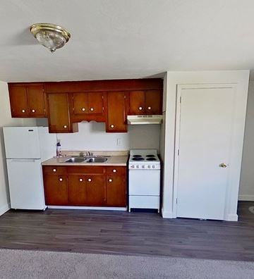 Redlion apartment for rent - A kitchen with wooden cabinets and a white fridge.