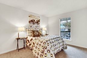 Virginia Beach apartment for rent - A bedroom with a bed, two lamps, and a painting on the wall.