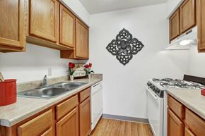 Manchester apartment for rent - A kitchen with wooden cabinets and a white stove top oven.