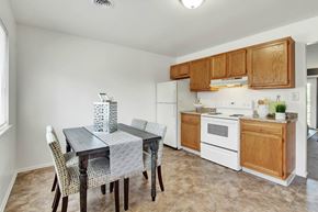 Harrisburg apartment for rent - A kitchen with a table and chairs in the foreground and a refrigerator and oven in the background.
