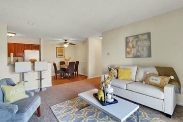 Fredericksburg apartment for rent - A living room with a grey couch, a white sofa, a grey and yellow rug, and a painting on the wall.