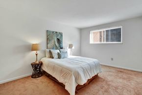 Harrisburg apartment for rent - A bedroom with a bed, two lamps, and a painting on the wall.