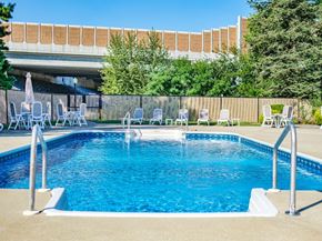 Harrisburg apartment for rent - A pool with chairs around it and a building in the background.