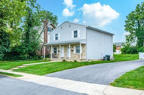 Hagerstown apartment for rent - A house with a grey facade is surrounded by greenery.